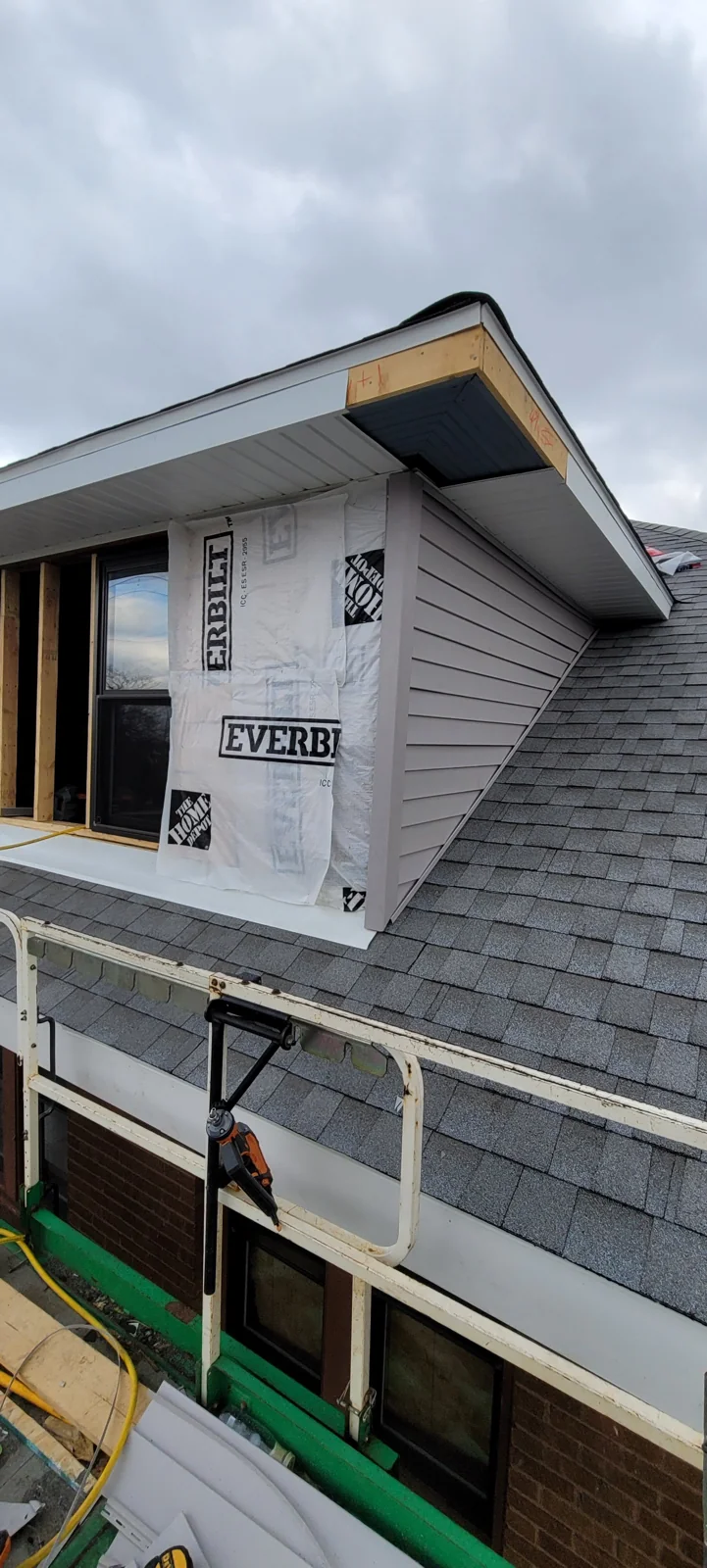Home addition under construction with Everwrap weather barrier and new roof shingles installed