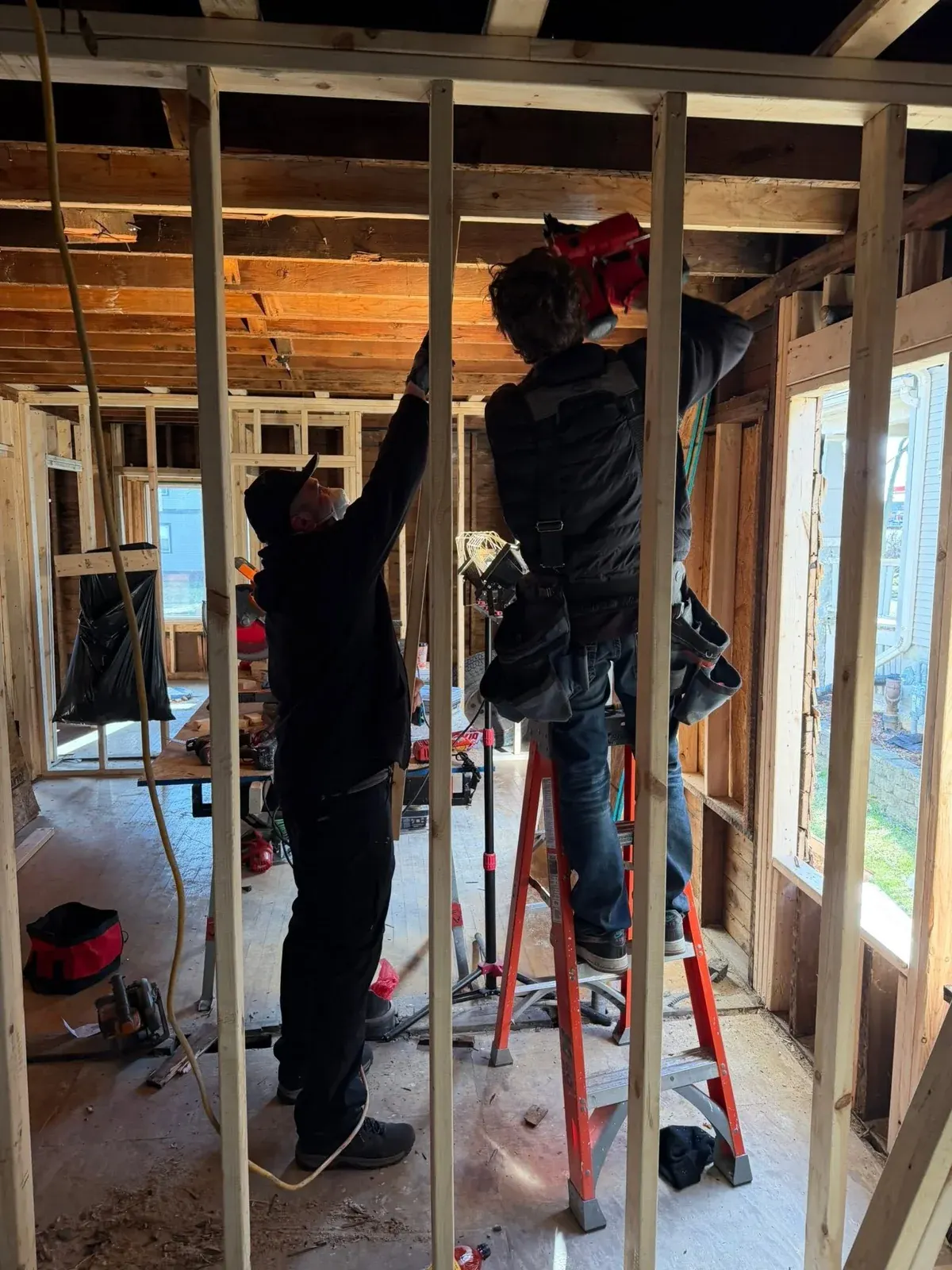 Two workers installing drywall framing in an unfinished residential interior space